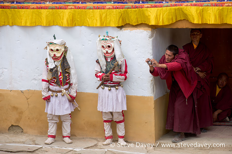 Masked Cham Dancers being photographed by a Buddhist monk, Korzo