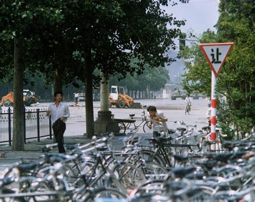 Bystanders flee tanks approaching from Tiananmen Square June 5, 1989. At center left between the trees in the background is the man in the white shirt who stopped the line of tanks in the well-known photos, dubbed “Tank Man.” Photo by Terril Jones/AP.